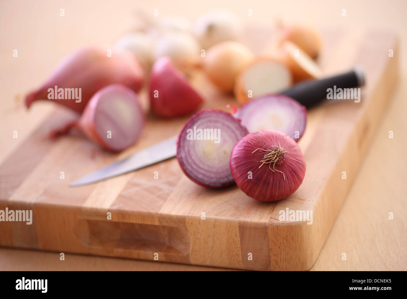 Sortiment von Zwiebeln und Schalotten auf Schneidebrett Stockfoto