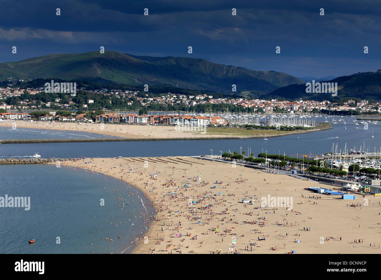 Sommer auf überfüllten Hondarribia Strand in Nordspanien mit der Mündung des Flusses Bidasoa und Hendaye Beach in Frankreich im Hintergrund Stockfoto