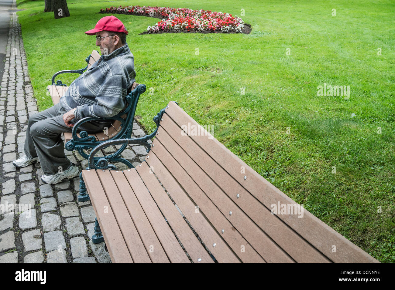 Ein älterer kanadischer Mann sitzt, suchen Sie unglücklich und tief in Gedanken, auf einer Parkbank in King es Square, St. John, Nova Scotia, Kanada Stockfoto