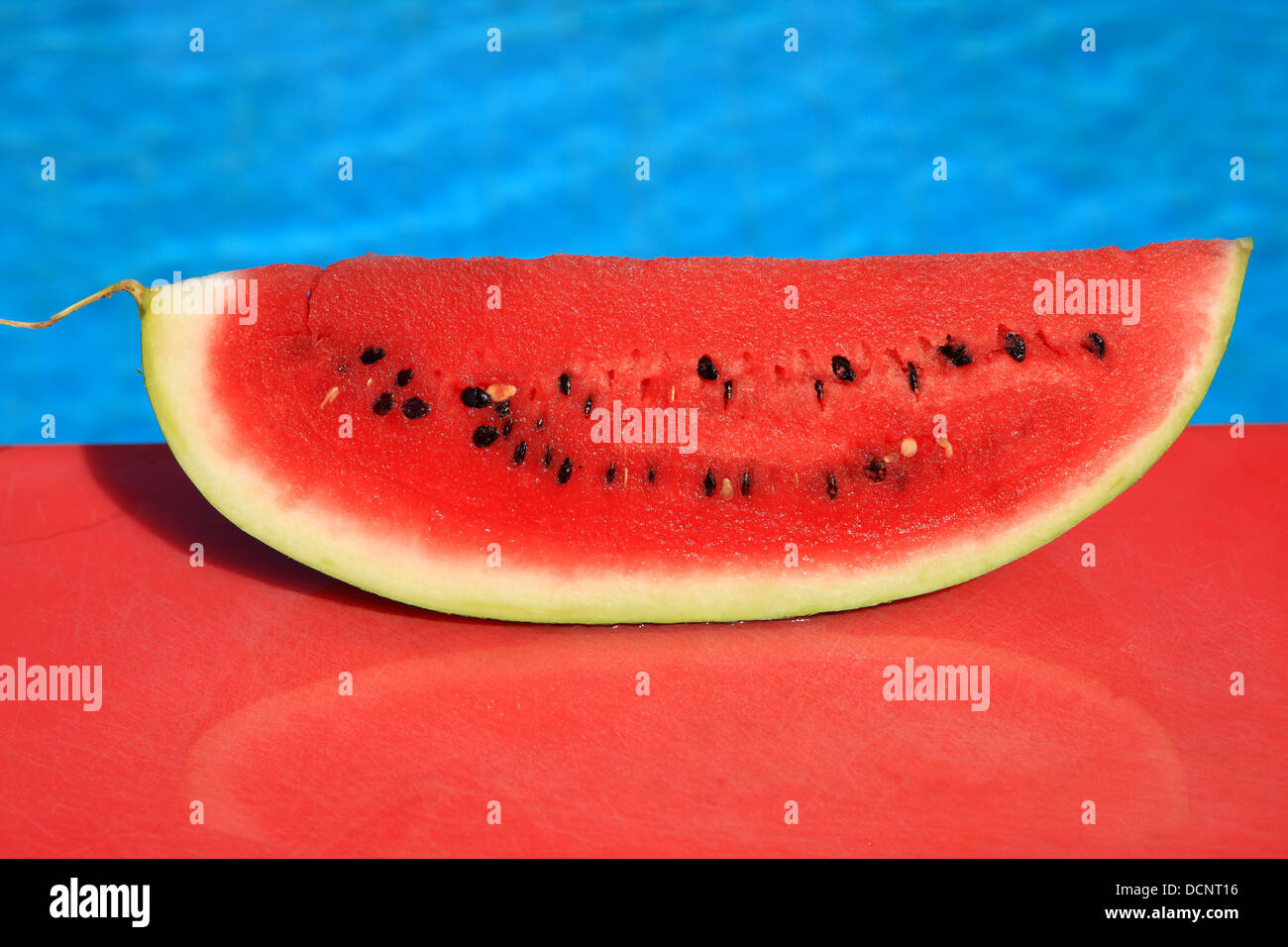 Wassermelone auf einem roten Schneidebrett von einem Schwimmbad Stockfoto