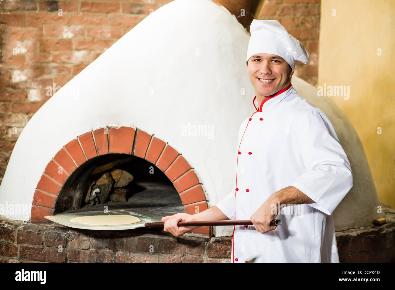 Koch legt Teig in den Ofen für Pizza, Stockfoto