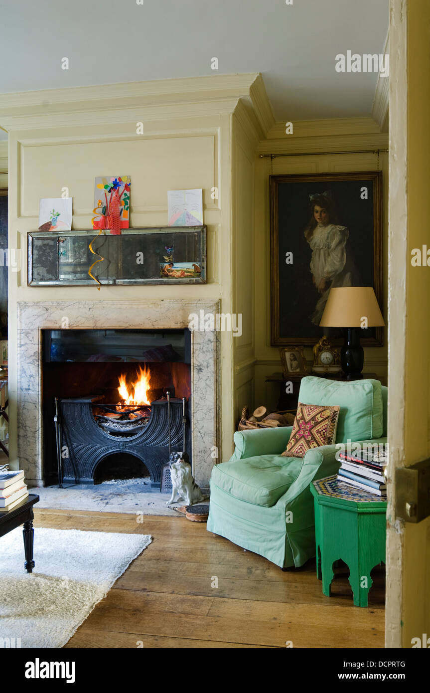 Grüne Sessel in der Ecke des Raumes mit achteckigen Beistelltisch und tiefen Kamin Stockfoto
