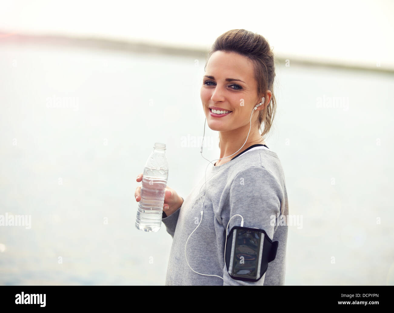 Lächelnd weibliche Wasser auf eine laufende Pause halten Wasser in Flaschen Stockfoto