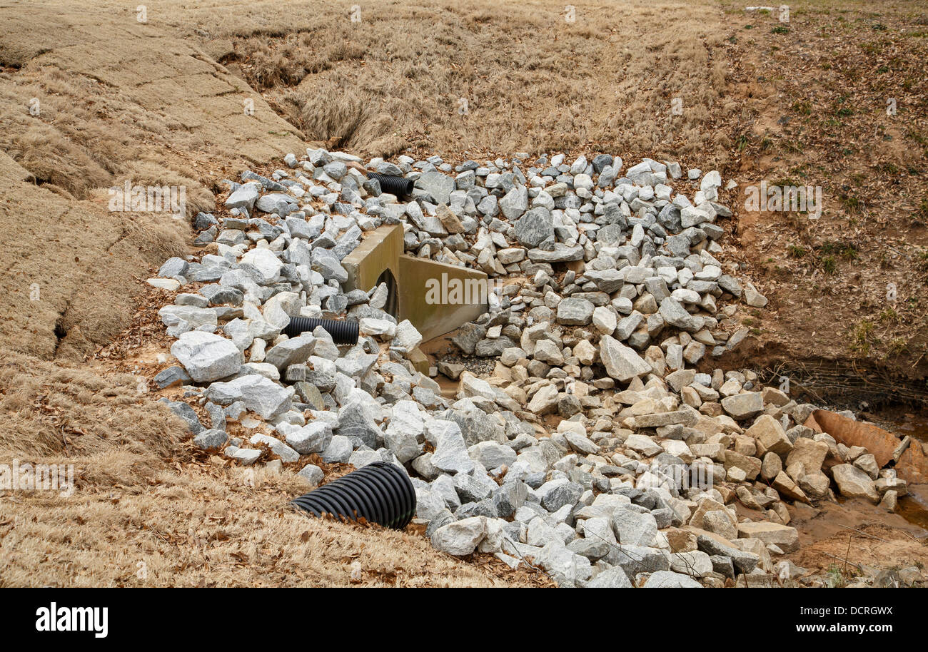 Schottersteine auf Beton- und Überlauf fließt aus einem See Stockfoto