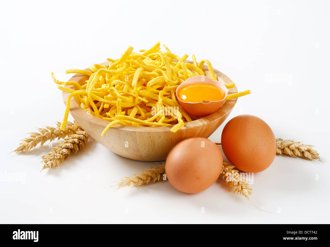 Dünne Spätzle in einer Holzschale, Ähren und Eiern Stockfoto