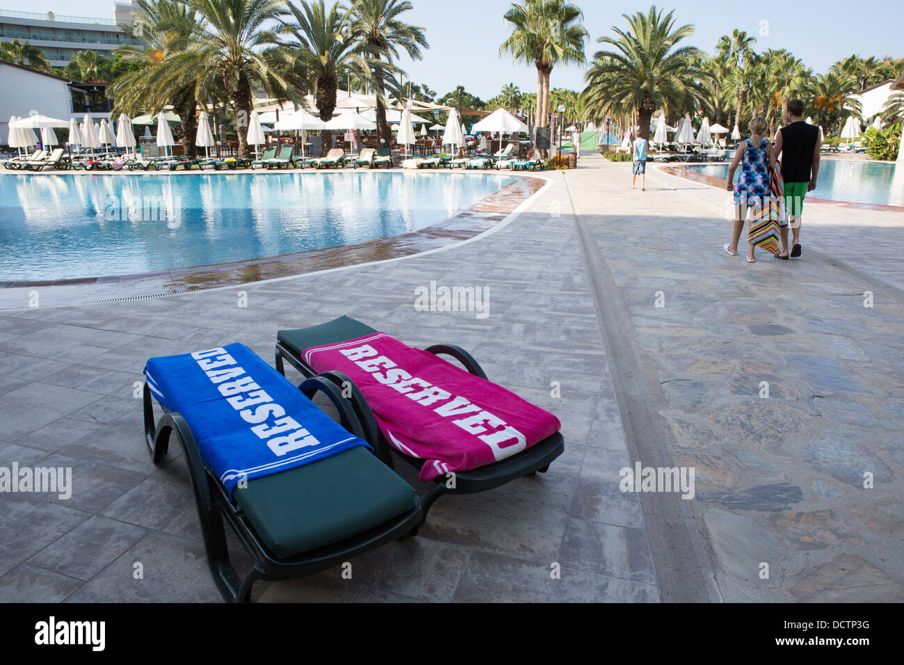 Zwei Sonnenliegen mit "reserviert" Handtücher neben einem Hotel-Schwimmbad Stockfoto