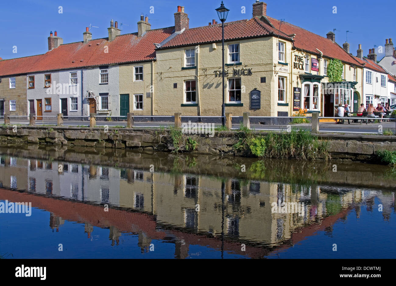 Der Buck Inn und die Terrasse des alten Hütten spiegelt sich in den Fluss Leven, heißen Sommertag, Great Ayton, North Yorkshire England UK Stockfoto