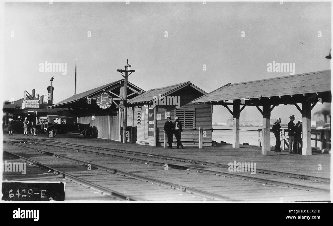 Das Bild zeigt die Landung der Fifth Street in Long Beach, Kalifornien, mit Regenschirmschuppen und dem Küstenpatrouillenbüro im Blick. Es erfasst eine typische Küstenlandschaft mit Infrastruktur für den Seeverkehr. Stockfoto