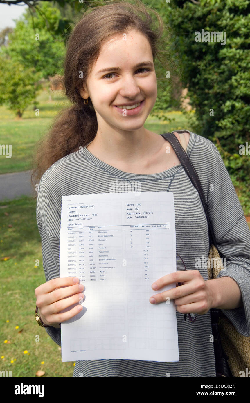 Eine glückliche Studentin hält ihre erfolgreiche GCSE Prüfung führt zu einer Kamera an einer Schule in London, England, UK. Stockfoto