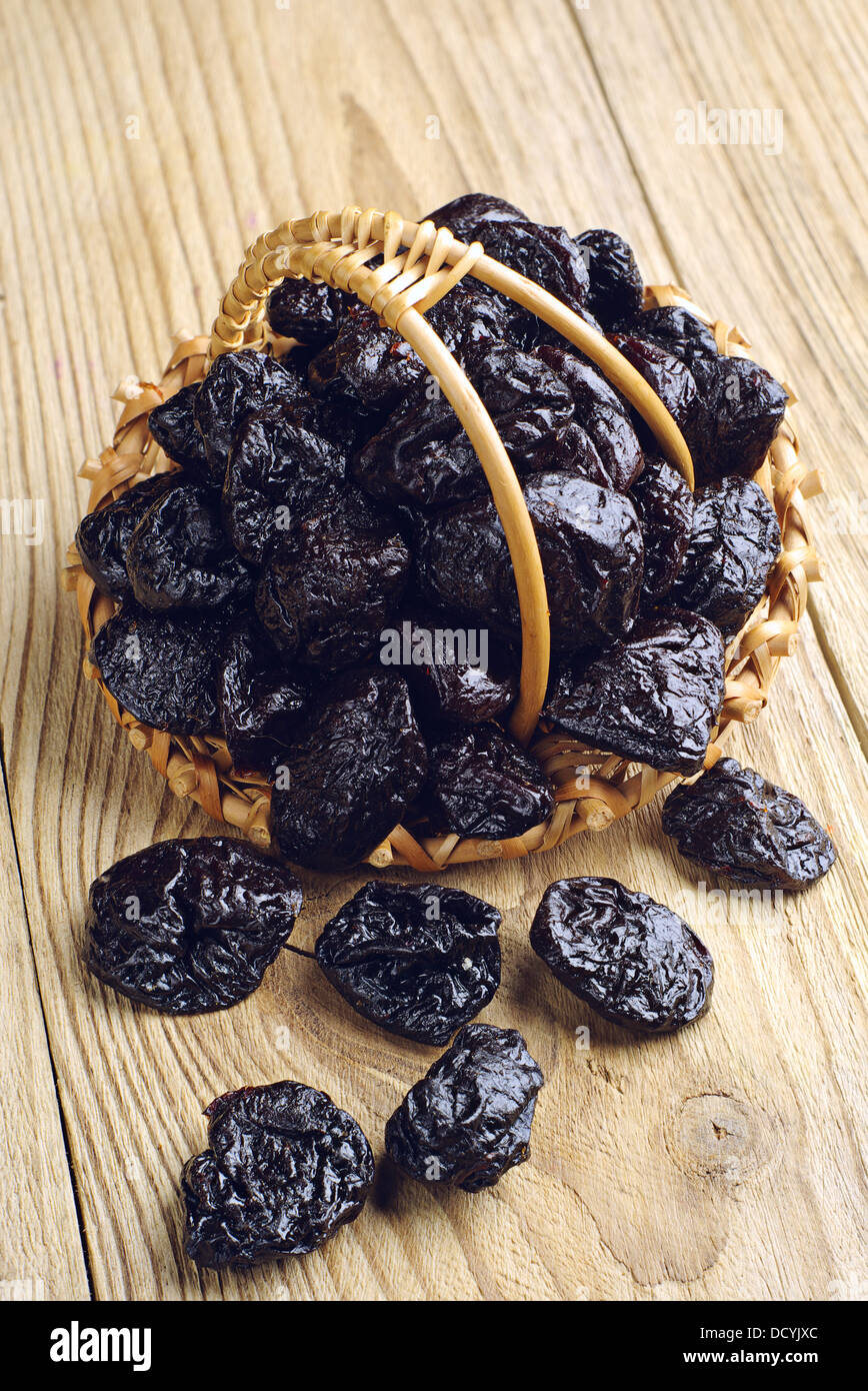 Getrocknete Pflaumen in einem Korb und in der Nähe von auf Holztisch Stockfoto