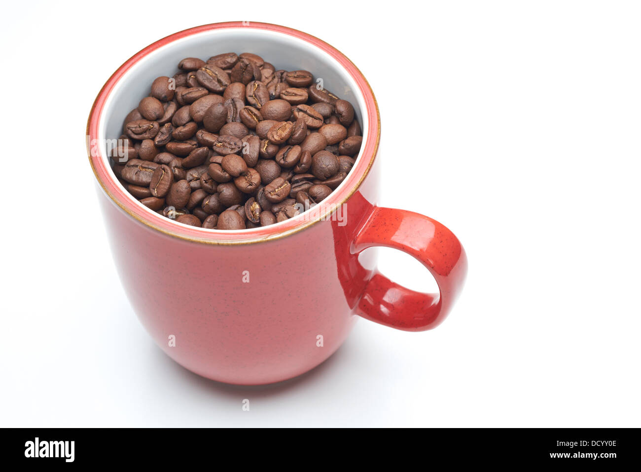 Rote Tasse mit Kaffeebohnen drin auf einem weißen Hintergrund isoliert. Stockfoto