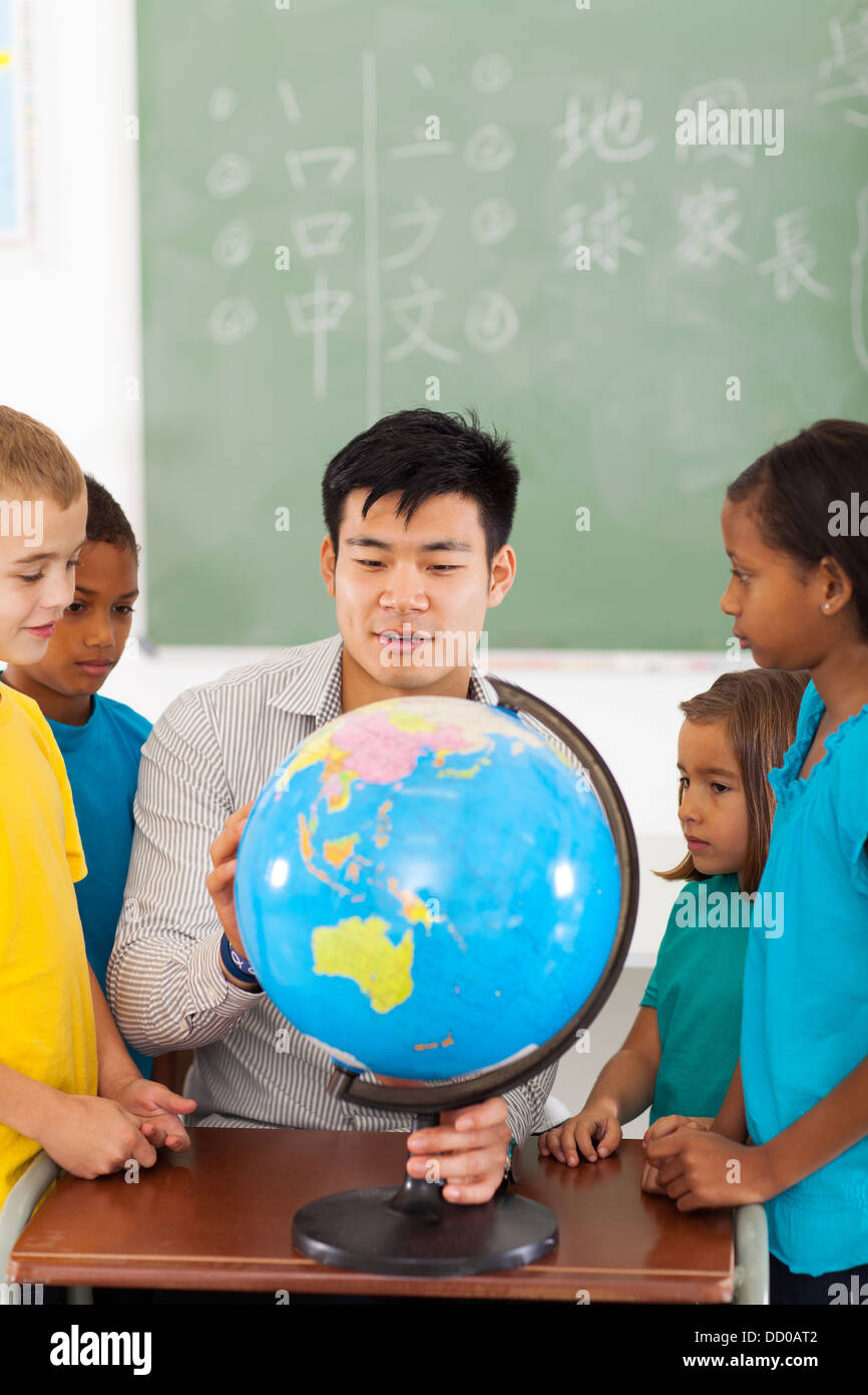 Gruppe Grundschüler und Lehrer betrachten Globus im Klassenzimmer Stockfoto