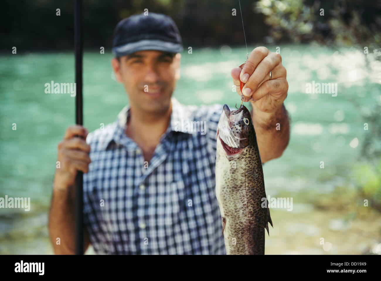 Mitte Erwachsene Fischer an Feiertagen am Fluss, entspannen und Forellen angeln. Fisch im Fokus Stockfoto