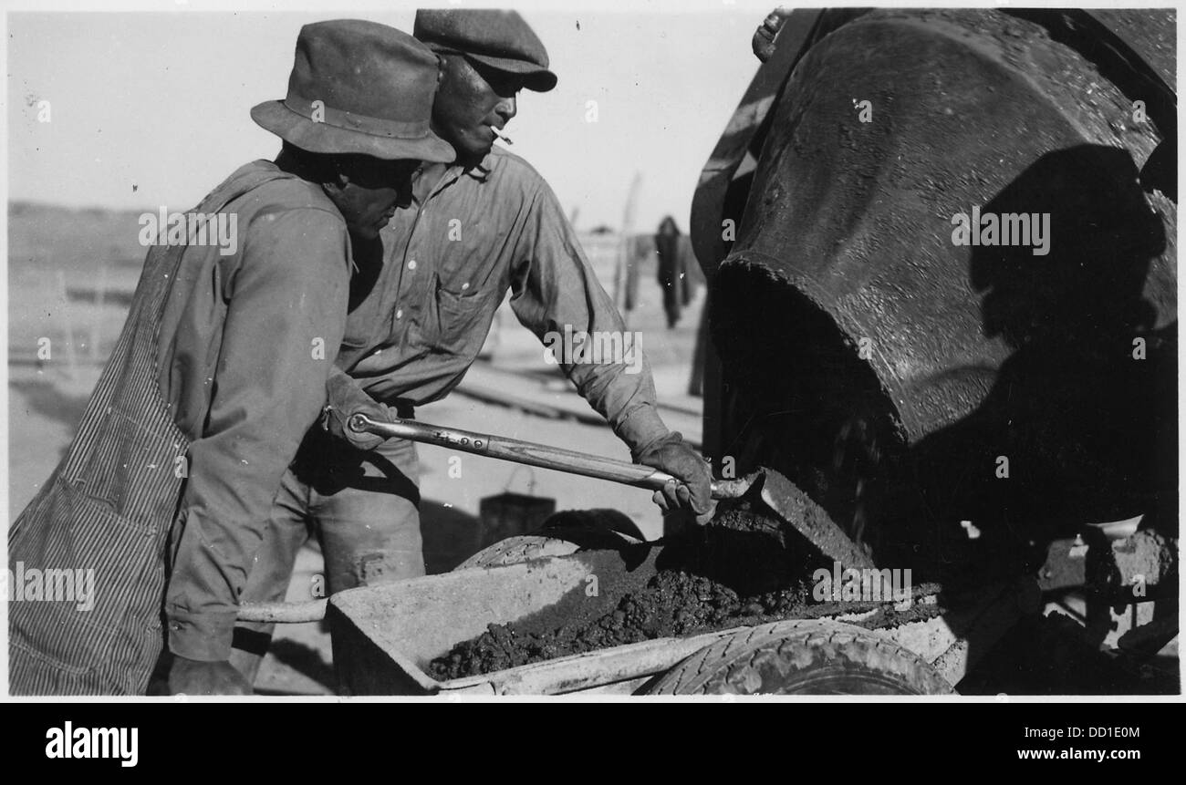 Am Oglala-Staudamm laden zwei Arbeiter eine Schubkarre mit Beton aus einem Mischer als Teil der laufenden Bauarbeiten zum Bau und zur Verstärkung des Staudamms. Stockfoto