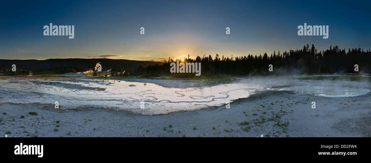 Der Sonnenuntergang wirft ein warmes Licht auf die heißen Quellen rund um die Old Faithful Geysir im Yellowstone National Park, Montana. Stockfoto