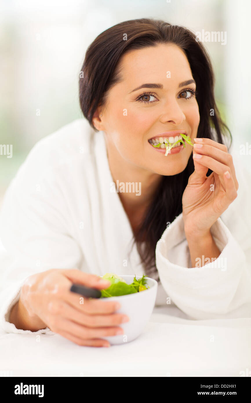 attraktive junge Frau essen Salat auf Bett Stockfoto