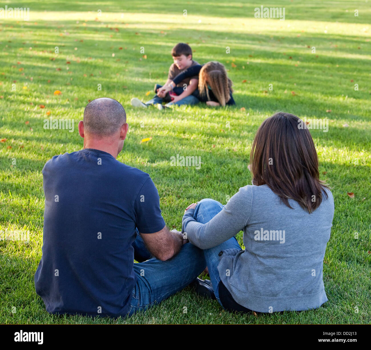Eltern sehen ihre Kinder spielen im Park; Beaumont, Alberta, Kanada Stockfoto