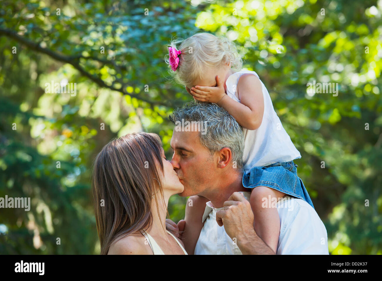 Mann und Frau küssen vor Kleinkind; Edmonton, Alberta, Kanada Stockfoto