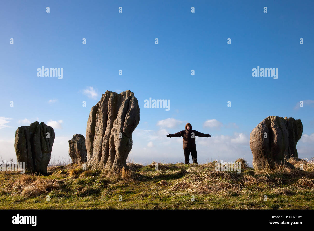 Eine Frau stand neben der Menhire von Duddo; Northumberland, England Stockfoto