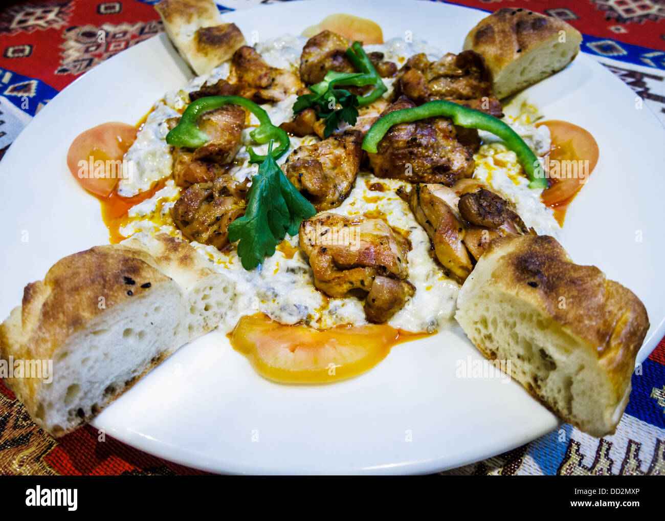 Türkische Mahlzeit von Char gegrilltem Huhn, Knoblauch und Auberginen Joghurtsauce und türkisches Brot auf einem weißen Teller serviert. Stockfoto