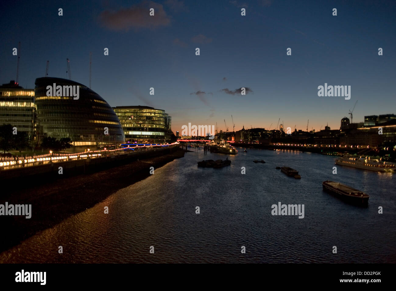 Blick auf den Sonnenuntergang von der Themse in London mit dem City-Lights im Wasser spiegelt. Stockfoto