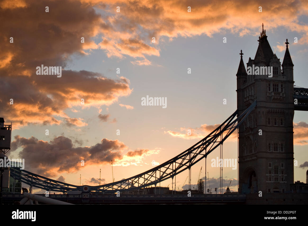 Blick auf den Sonnenuntergang von der Tower Bridge über die Themse in London mit orange leuchtenden geschwollenen Wolken hinter sich. Stockfoto