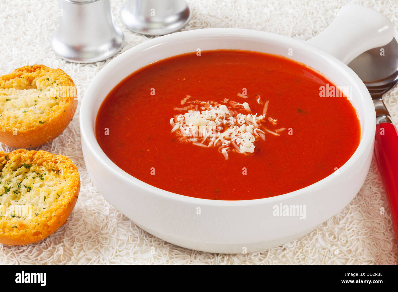 Tomatensuppe - eine Schüssel mit Tomatensuppe mit Knoblauch Toast, garniert mit einer Prise Parmesan, auf einem weißen Hintergrund. Stockfoto