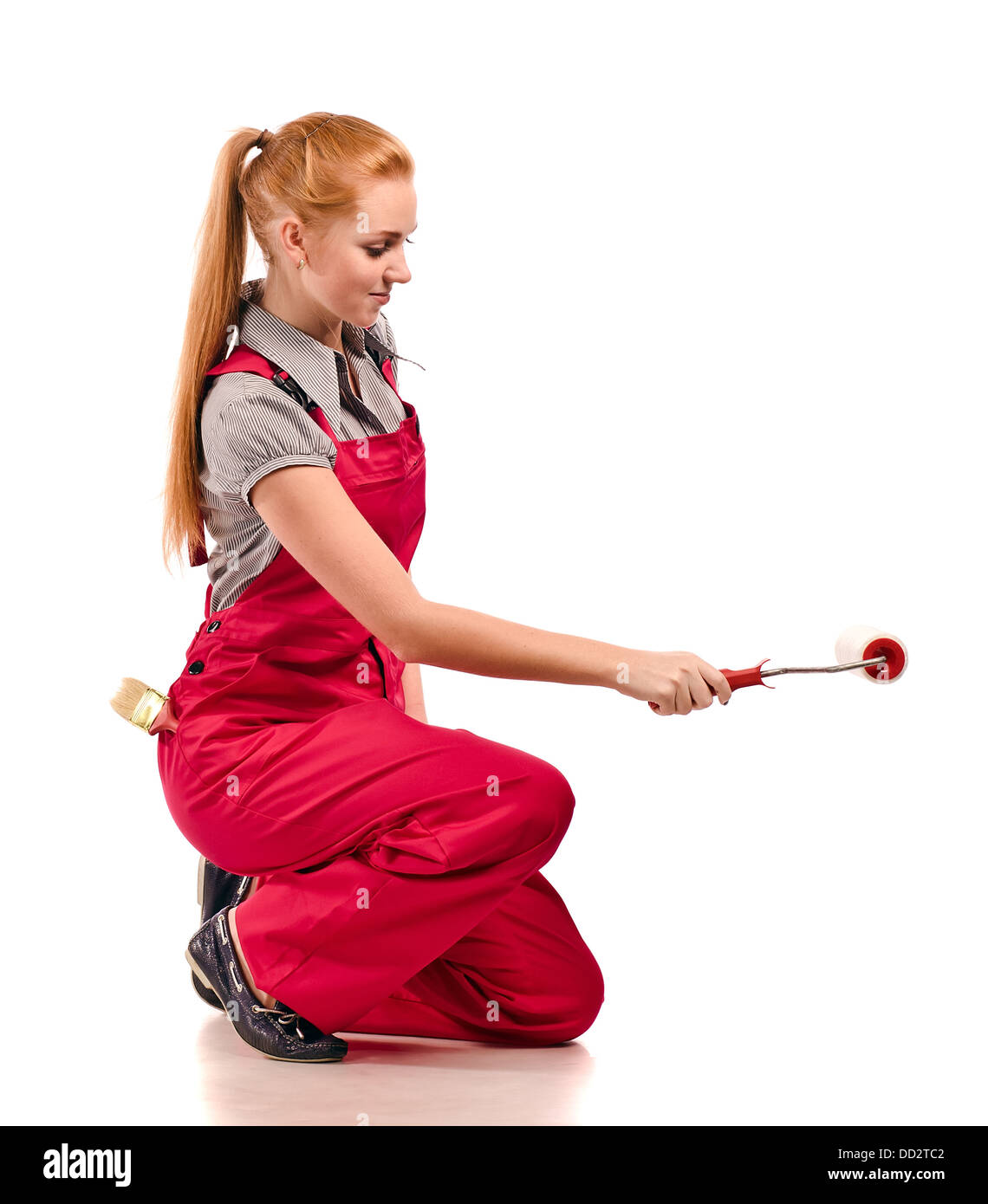 Junge Frau im roten Overall mit Malwerkzeugen, isoliert auf weiss Stockfoto