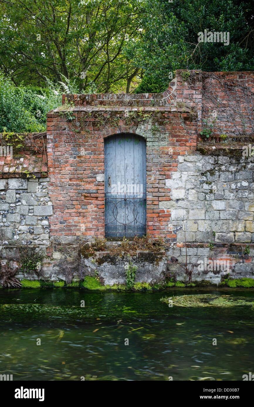 Alte Steinmauer und Tür an einem Flussufer in Winchester, Hampshire, UK Stockfoto