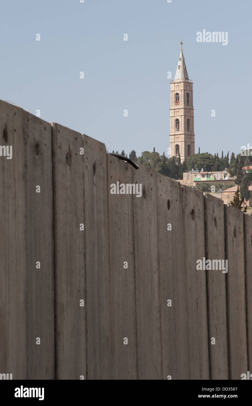 Ein Kirchturm ragt der israelischen Trennmauer, die palästinensischen Nachbarschaften in Ost-Jerusalem teilt. Stockfoto