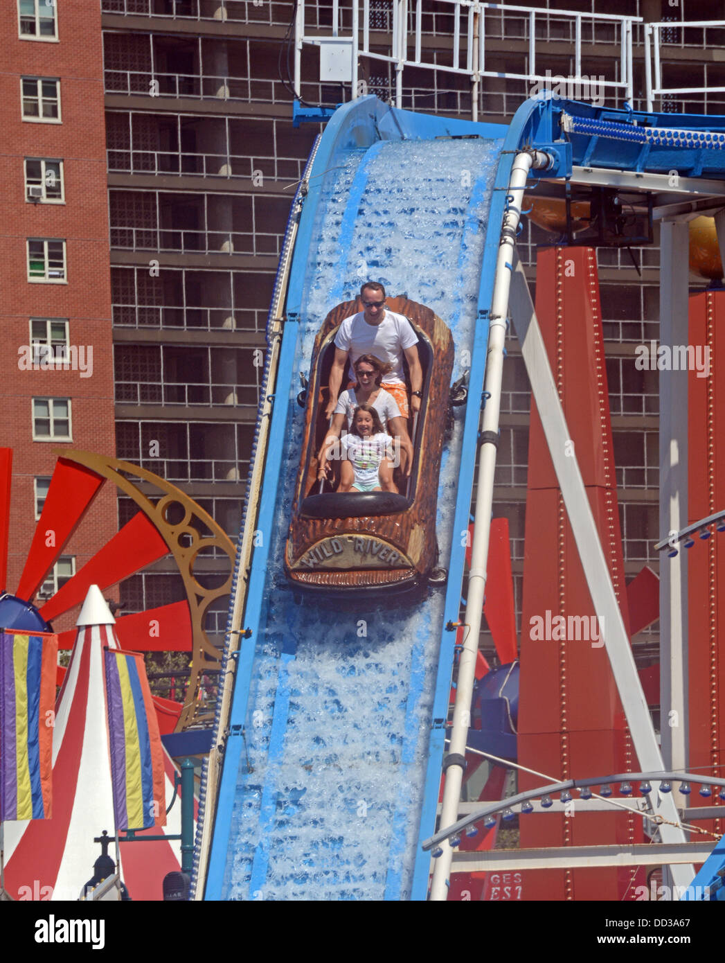 Mit Wohnhäusern im Hintergrund reitet eine Familie Wild River Attraktion im Luna Park auf Coney Island, Brooklyn New York Stockfoto
