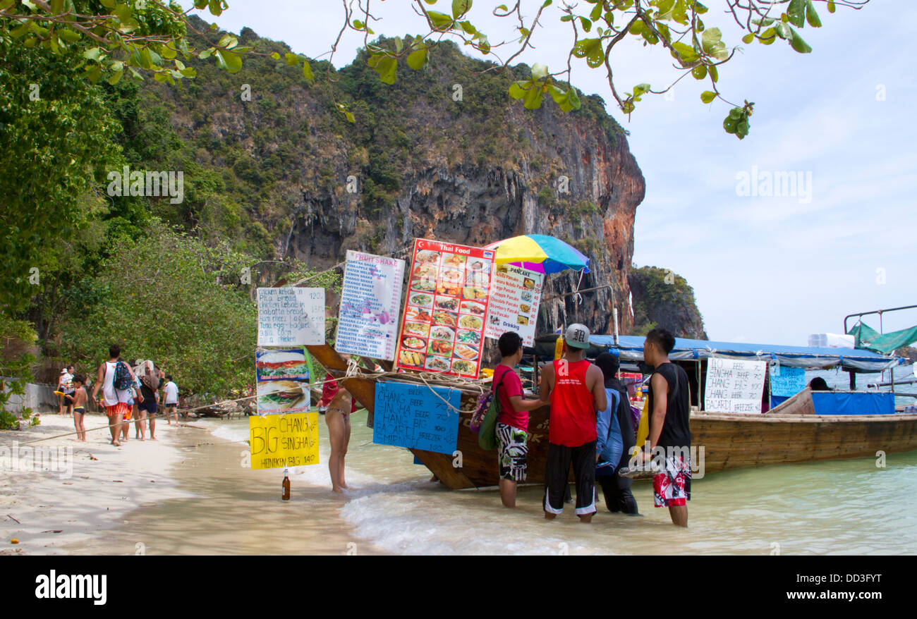 Die Leute kaufen Essen in einem Restaurant-Boot am Strand von Hut Phra Nang in Railay verankert. Stockfoto