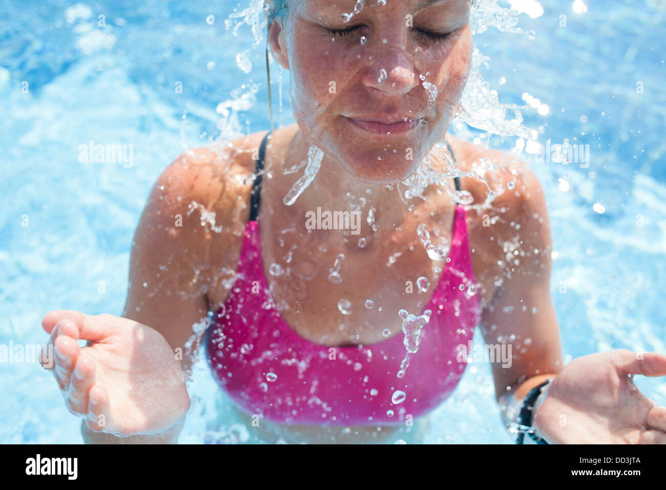 Glücklich weibliche Schwimmer Spritzwasser im Gesicht mit Augen geschlossen, während im Schwimmbad Stockfoto