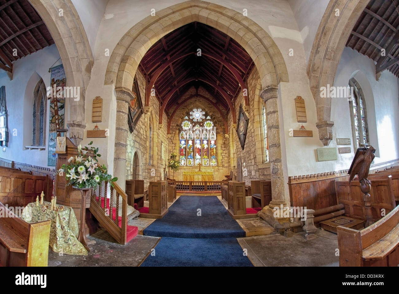 Ein blauer Teppich führt hinunter die Mitte der Kirche gegenüber dem Glasfenster; Whittingham, Northumberland, England Stockfoto