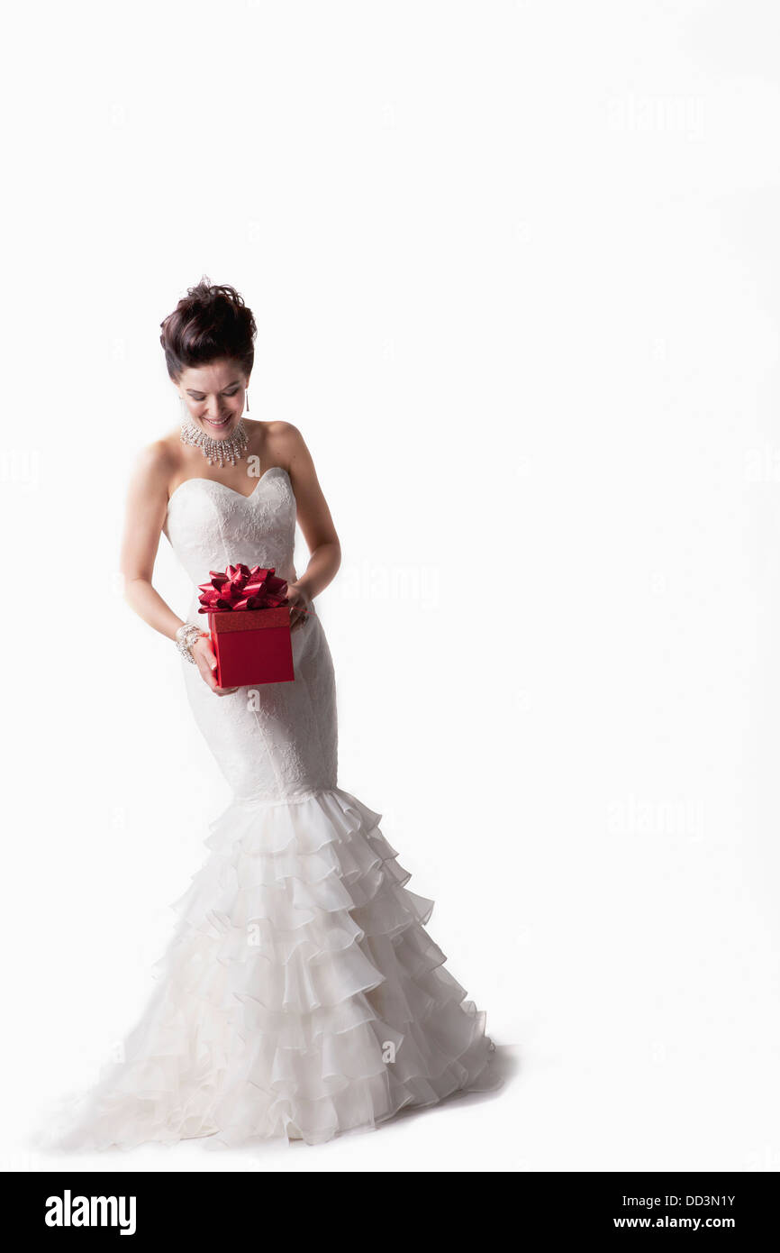 Eine Braut posiert mit einer roten Geschenkbox vor einem weißen Hintergrund; Nashville, Tennessee, Vereinigte Staaten von Amerika Stockfoto