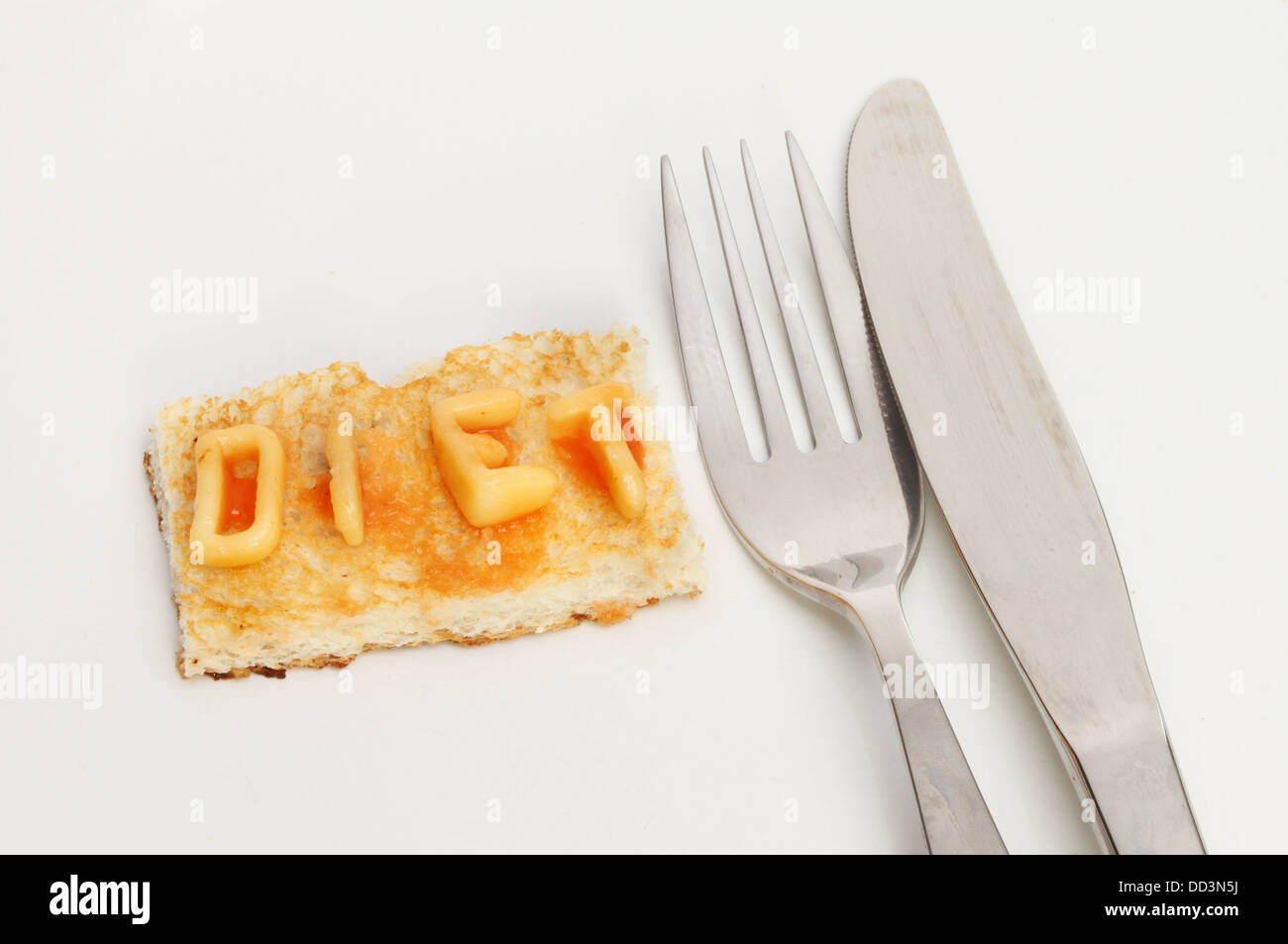 Diät-Konzept, kleines Stück Toast mit Diät geschrieben, mit Alphabet Spaghetti mit Messer und Gabel auf einem Teller Stockfoto