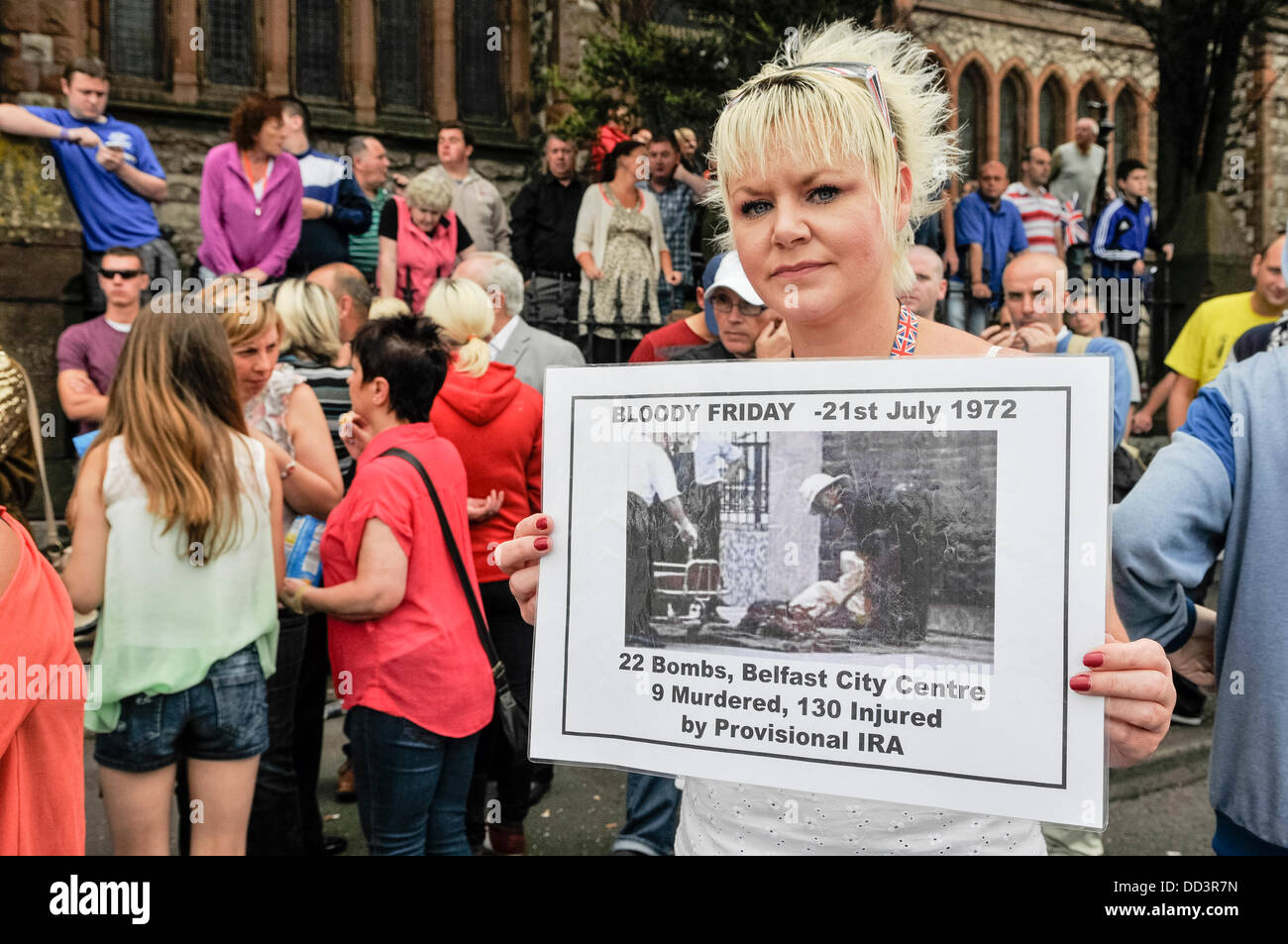 Belfast, Nordirland. 25. August 2013. Liz Bingham, Tochter des ermordeten UVF Chef John Bingham, protestiert gegen eine republikanische Parade, wie hält sie eine Banner mit einem Foto von "Blutiger Freitag", 21. Juli 1972, als die IRA 22 Bomben im Stadtzentrum von Belfast, explodiert 9 Menschen getötet und verletzt wurden 130 Credit: Stephen Barnes/Alamy Live News Stockfoto