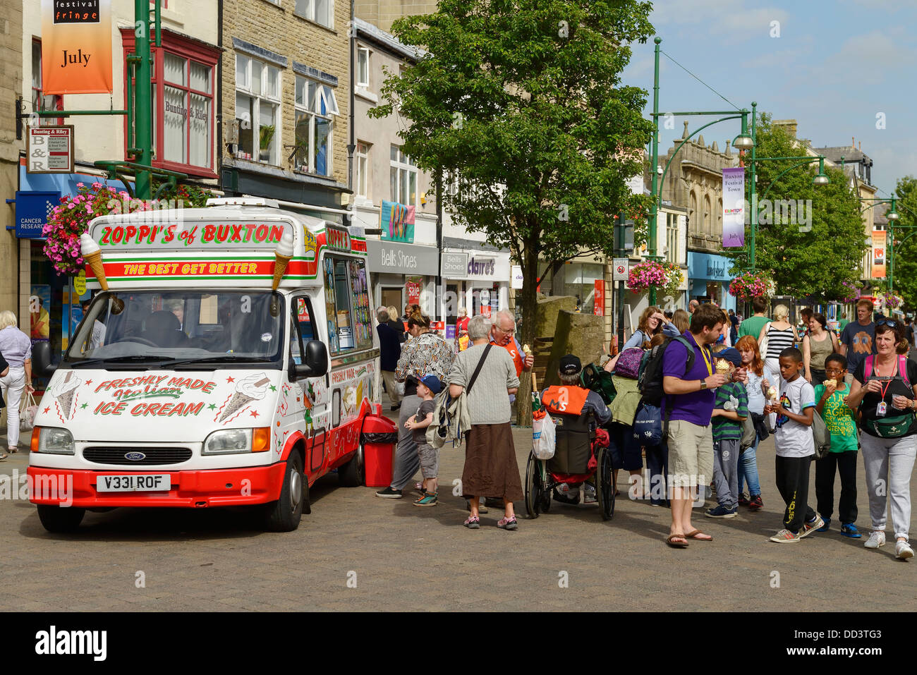 Touristen, Besucher und Kunden in der Nähe von einem Eiswagen auf der Haupteinkaufsstraße in Buxton UK Stockfoto