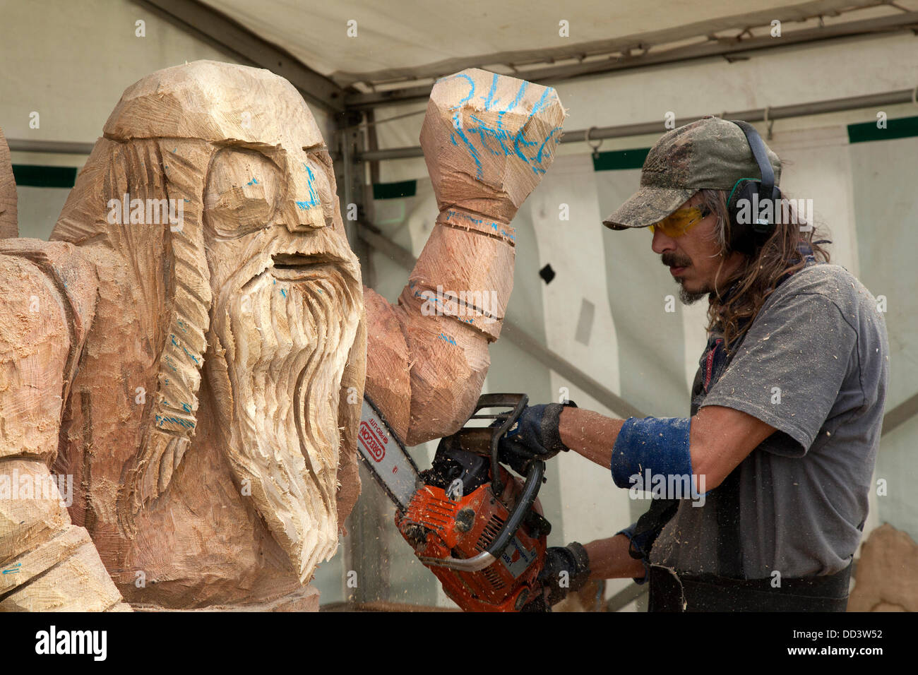 Kettensäge-Künstler bei der Arbeit in Tabley, Khetan, Großbritannien, August 2013. Wikingerfigur Gesicht geschnitzt von Bruce Thor aus den USA beim 9. English Open Chainsaw Carving Competition, Kettensäge schnitzen, Gartenskulptur, Statue, Wald, Waldhandwerk auf dem „The Keshire County Showground“, Game and County Fair, Großbritannien. Die Kettensägen-Kunstschnitzer verwenden Holz (manchmal riesige Stücke), um schöne Schnitzereien von bis zu 20 Fuß hoch zu produzieren. Wenn jeder ein begehrtes Kunstwerk wird. Holzskulptur, Sägemehl, Bildhauer, Holz, Späne, Log, professionell, arbeiten, Kunst, Künstler, Schnitt, Kettensäge, Kunstwerk aus grobem Holz. Stockfoto