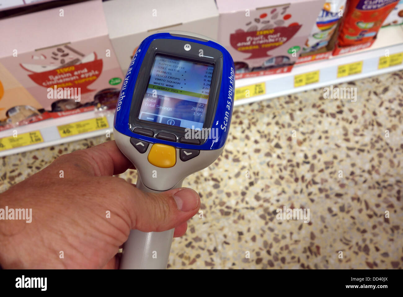 Ein Shopper mit einem Shop und Scan-Gerät in einem Tesco Speicher, UK Stockfoto