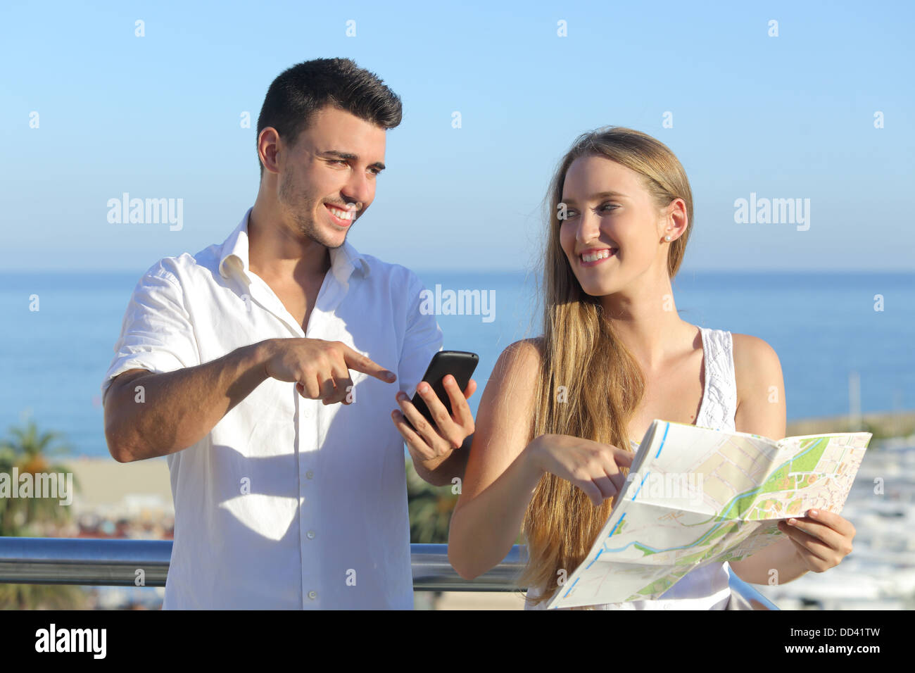 Paar diskutieren Karte oder Smartphone Gps in den Ferien mit dem Meer im Hintergrund Stockfoto