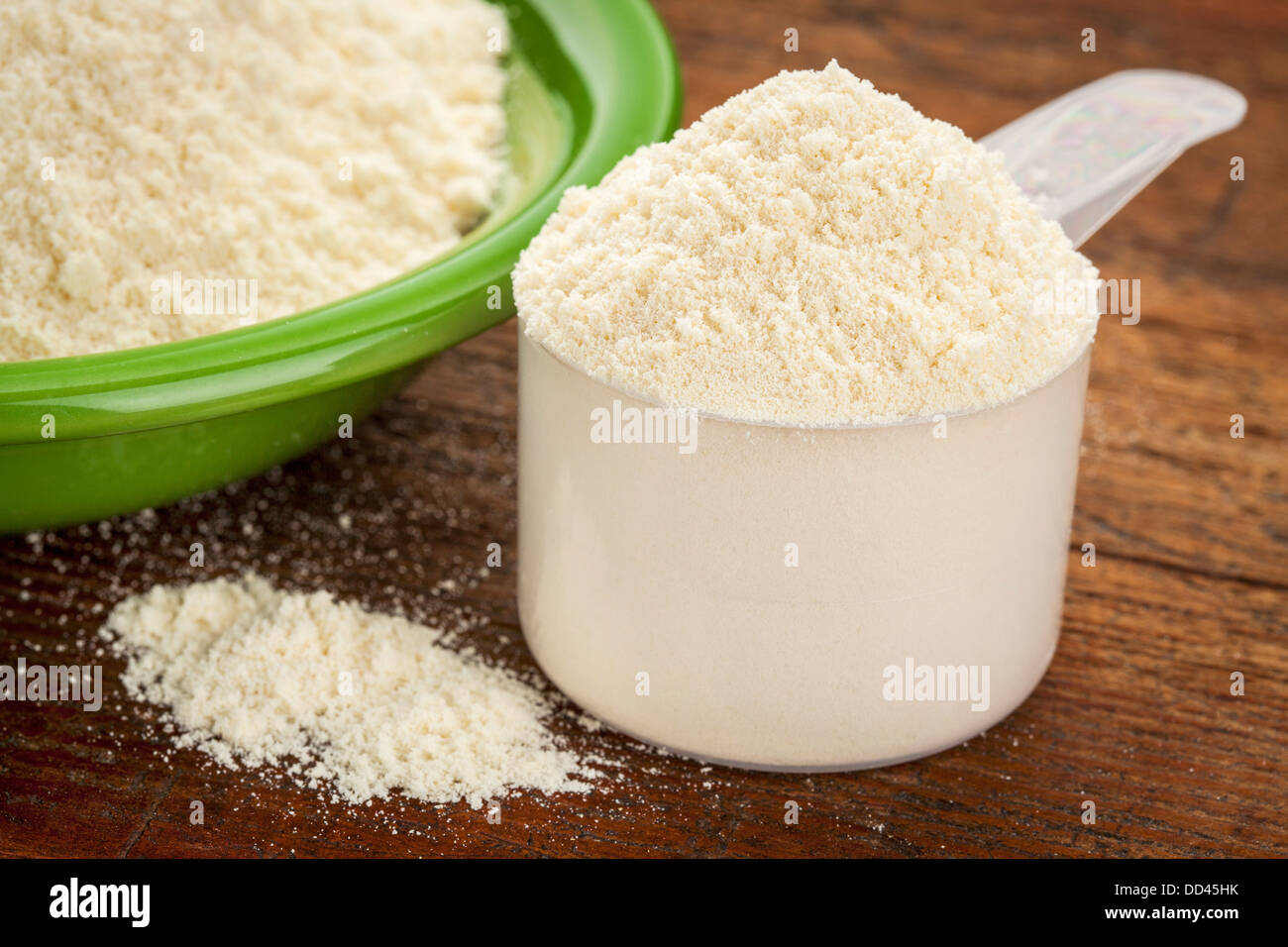 Messbecher von Molke-Protein-Pulver mit einer Schüssel auf Holzuntergrund Stockfoto