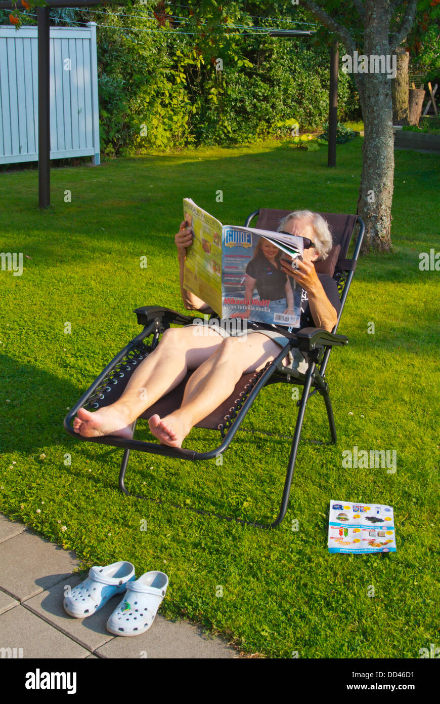 Frauen in ihren frühen 70er Jahren lesen Zeitung im Garten westlichen Finnland-Nordeuropa Stockfoto