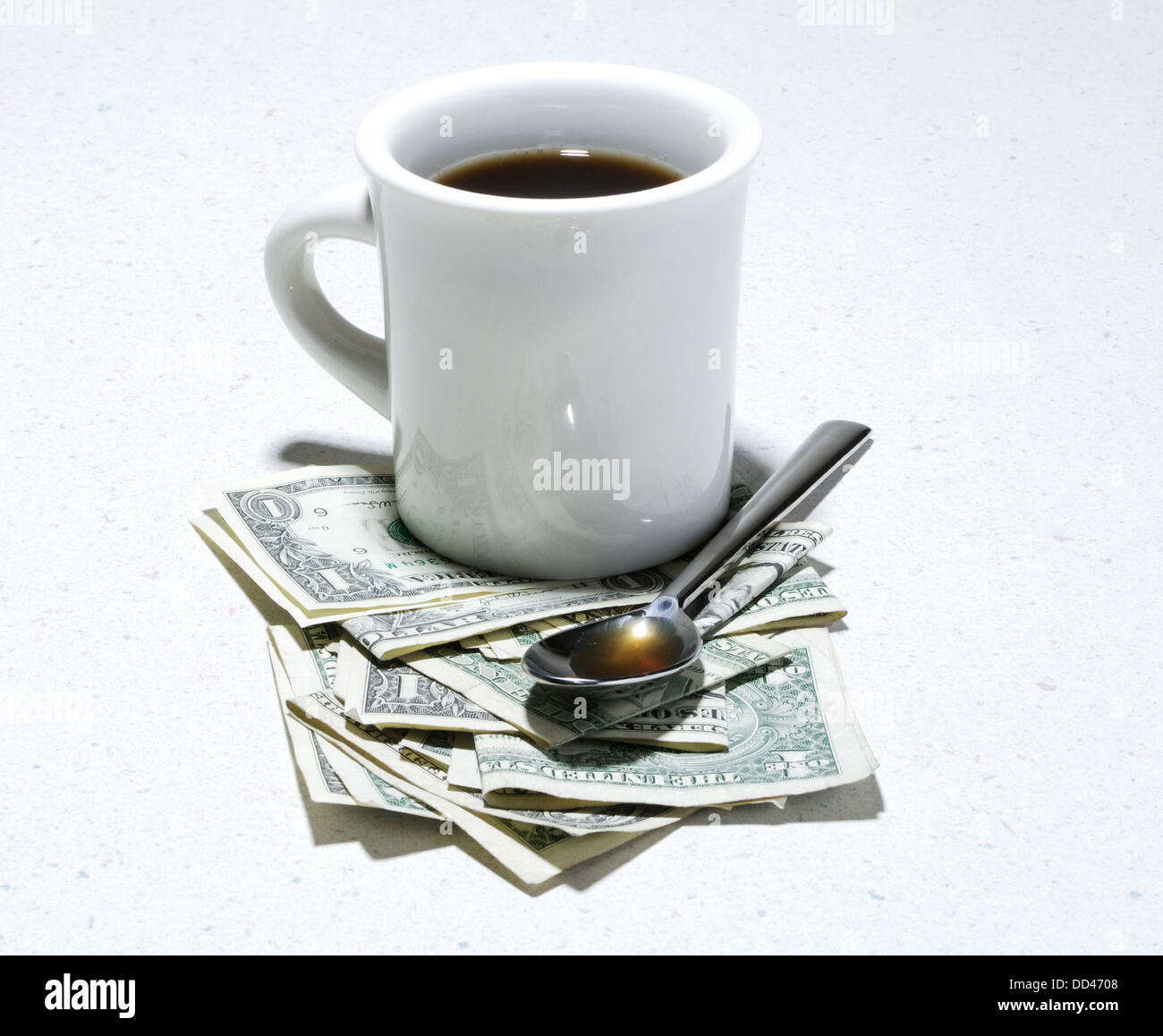 Eine weiße Kaffeetasse und Löffel mit US-Währung. Stockfoto