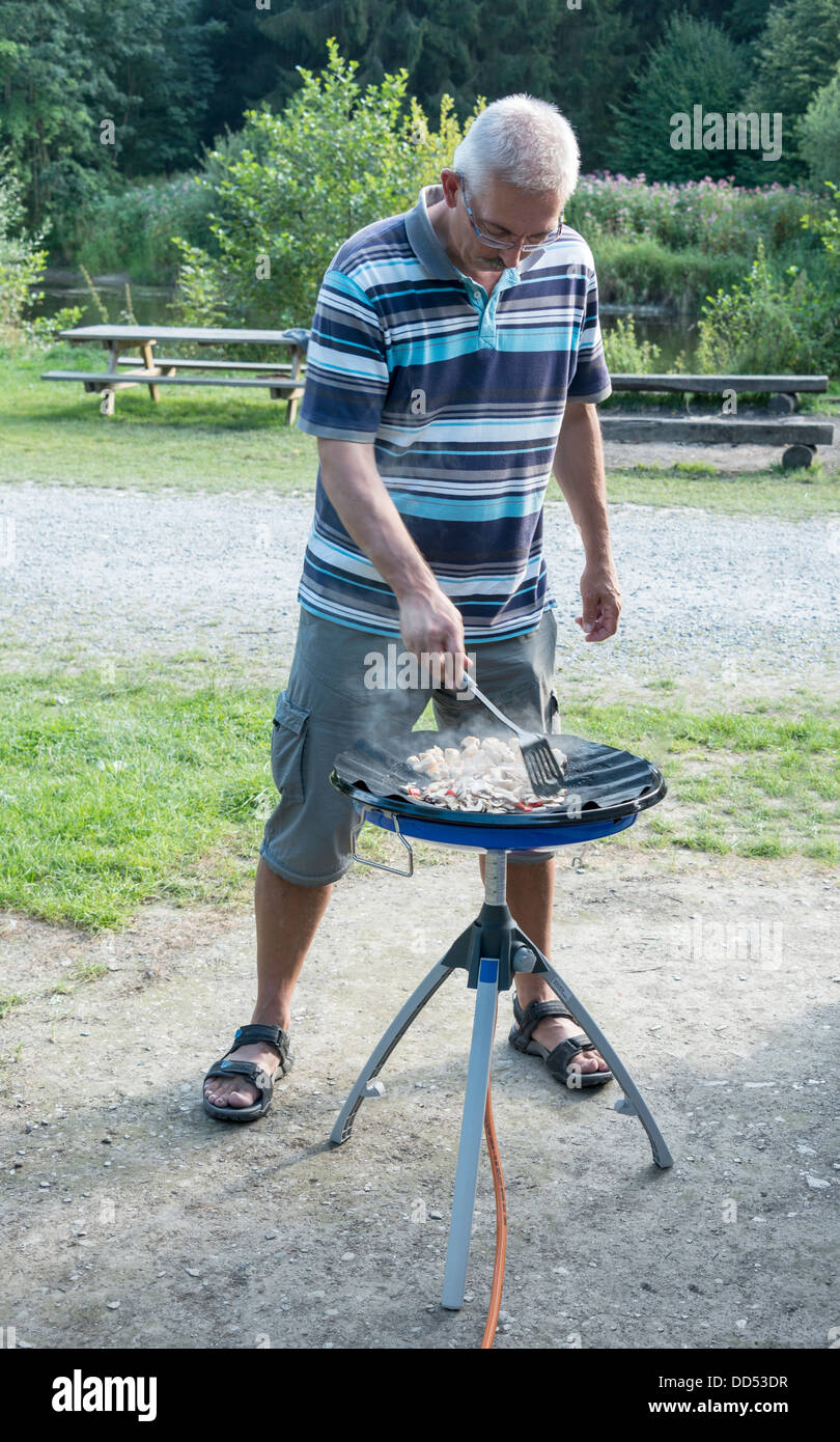 Mann, Kochen mit Gas-Komfort auf dem Campingplatz Stockfoto