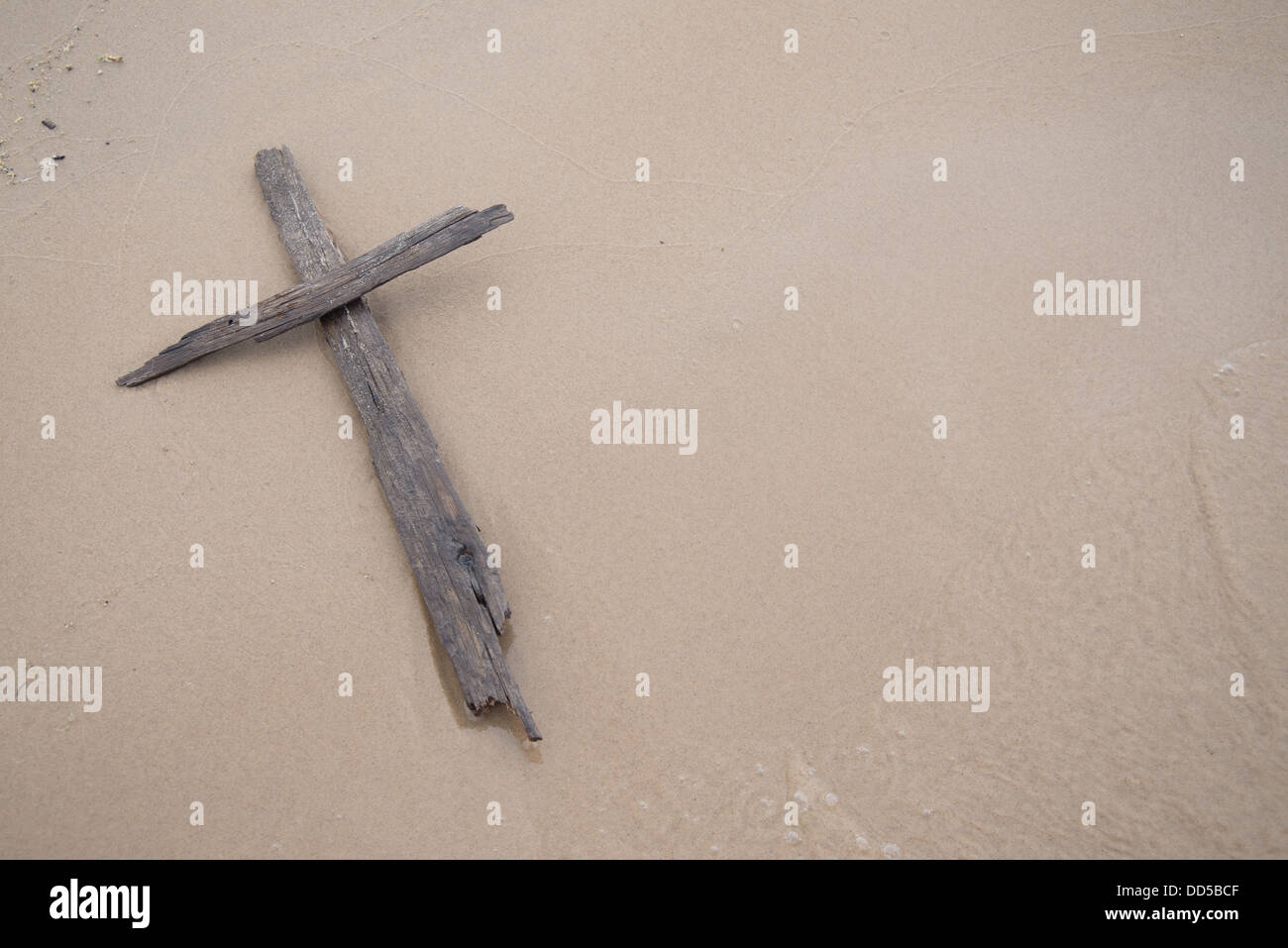 Ein Kreuz aus Treibholz Handauflegen im Sand am Strand. Stockfoto