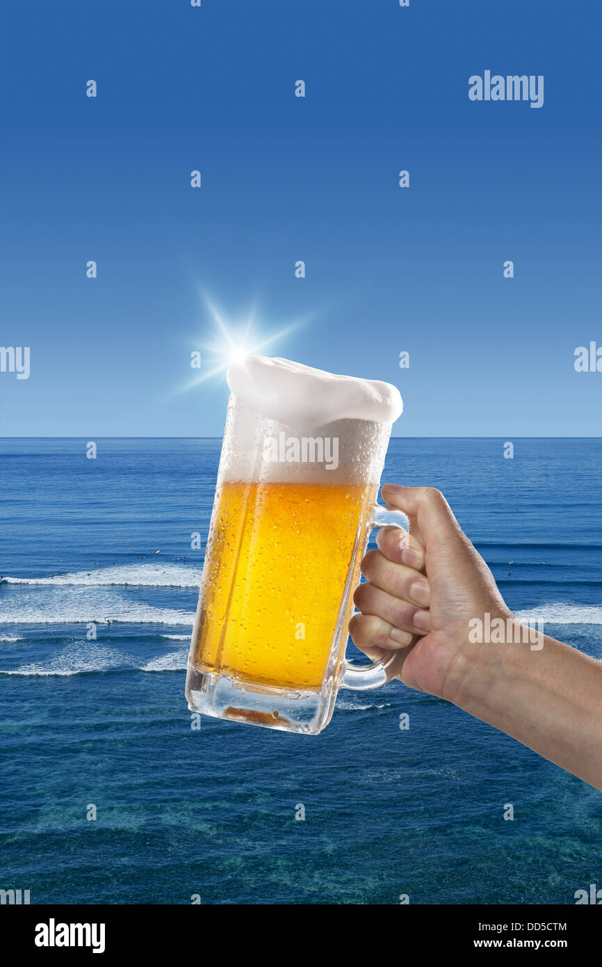 Glas Bier und Meer im Hintergrund Stockfoto