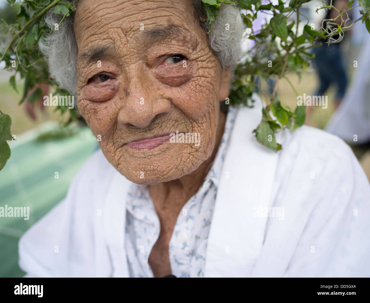 96 Jahre alten Kaneshi Fusae tragen Kranz von Ryukyu-Botanzuru am Unjami-Festival am Kouri Insel Okinawa Stockfoto