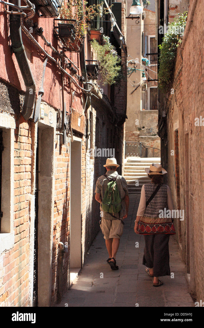 Touristen zu Fuß entlang einer schmalen Straße in Venedig. Stockfoto