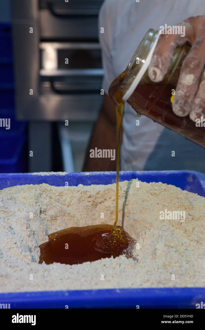 Bäcker fügt Honig zu einem Teig Mehl Stockfoto
